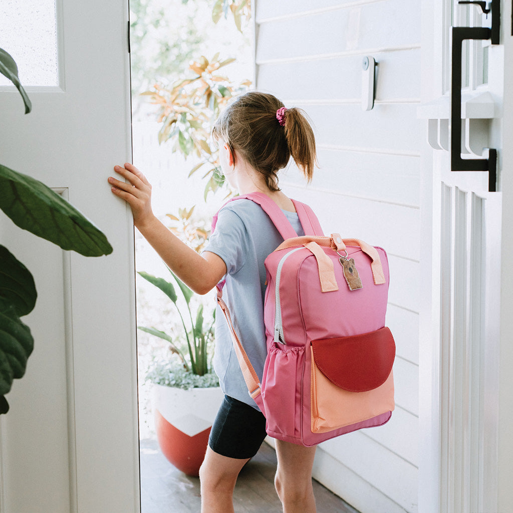 school girl walking out front door with pink school bag and australian quokka key chain 