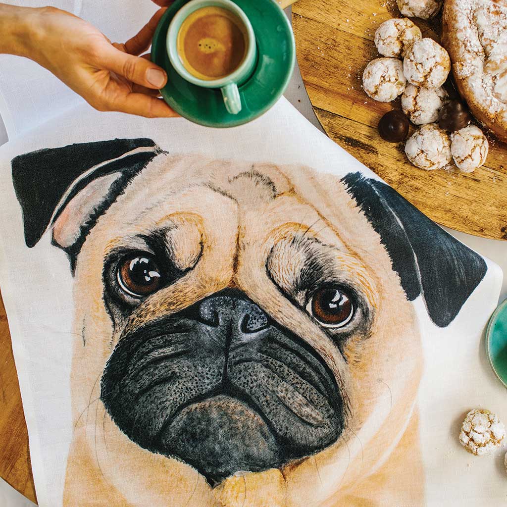 white linen tea towel with fawn pug watercolour artwork in kitchen with coffee and dessert