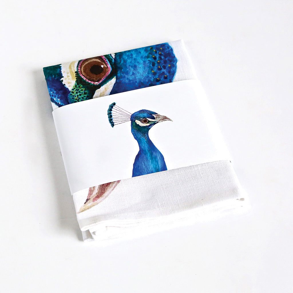 white linen tea towel with peacock watercolour artwork packaged