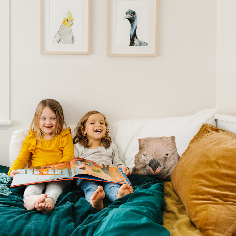 kids bedroom with girl and boy reading underneath animal art prints and animal pillowcase 